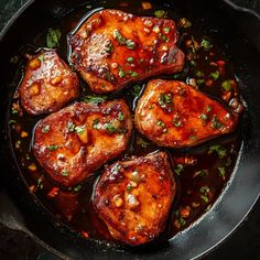 pork chops are cooked in a skillet with sauce and garnishes