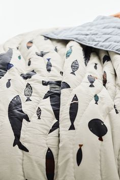 an unmade bed with black and white whales on it