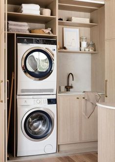 a washer and dryer in a small room with open shelves on the wall