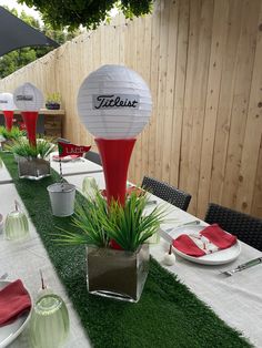 a table set up for a party with red and white plates, napkins, and paper lanterns