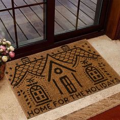 a door mat that says home for the holidays with a house and flowers on it