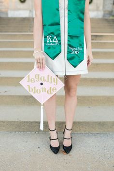 a woman wearing a green vest holding a pink and white sign that says legally blonde