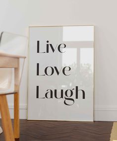 a white framed poster with the words live love laugh on it next to a chair