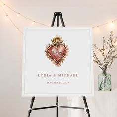 an easel with a heart on it next to a vase and string lights in the background