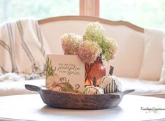 there is a bowl with flowers and pumpkins in it on the table next to a card