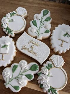 decorated cookies on a wooden table with white and green decorations in the shape of flowers