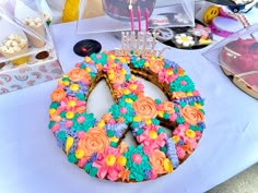 a peace sign cake on a table with cupcakes and desserts in the background