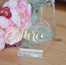 there is a glass vase with flowers in it and the word three written on it