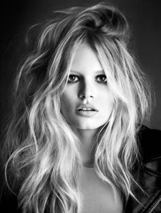 a black and white photo of a woman with long blonde hair wearing a leather jacket