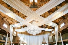 the inside of a wedding venue with white drapes and chandelier hanging from the ceiling