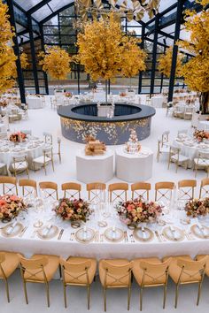 the tables are set up for a formal dinner in an orange and white setting with gold accents