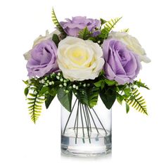 purple and white flowers are in a clear vase with greenery on the side, against a white background