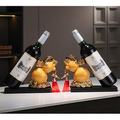 two wine bottles are placed in the shape of animals on a table with red and gold decorations