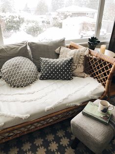 a day bed with pillows on it in front of a window overlooking the snow covered yard