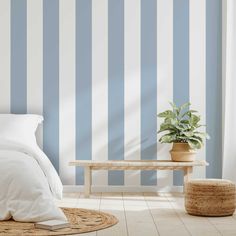 a bedroom with blue and white striped wallpaper, a bench and rugs on the floor