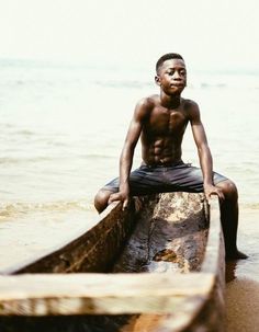 a young man sitting on top of a boat in the water