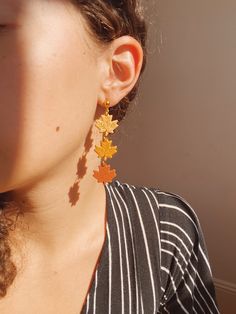 a close up of a person wearing earrings with leaves hanging from the back of them