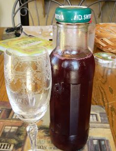 there is a bottle and a glass on the table next to each other, both filled with liquid