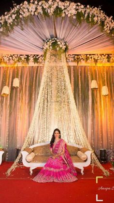 a woman sitting on a couch in front of a decorated stage with flowers and lights