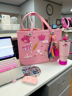 a pink purse sitting on top of a desk next to a laptop computer and cup