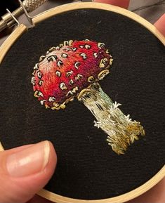 a hand embroidered picture of a mushroom on a black background