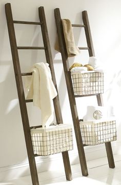 an old wooden ladder with baskets on the bottom and two towels hanging from it's sides