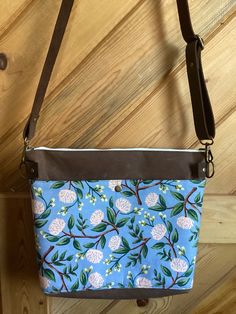 "This waxed canvas bag is the perfect size for those who don't want to carry a huge purse with them. The exterior of each bag is brown waxed canvas, with a deep and wide lined cotton floral front pocket with a snap to keep your phone tucked safely away. Inside, a light blue Rifle Paper Co floral cotton lining adds a little feminine flair to the bag. A 7\" deep pocket with three sections inside will help you organize your things, including a pocket that is well sized for a phone. The interior fit Brown Cotton Shoulder Bag With Zipper Pocket, Brown Cotton Crossbody Canvas Bag, Brown Canvas Bag With Snap Closure, Brown Canvas Shoulder Bag With Snap Closure, Brown Cotton Canvas Bag With Removable Pouch, Brown Cotton Canvas Bag With Adjustable Strap, Brown Canvas Bag With Zipper Pouch, Helena Montana, Waxed Canvas Bag