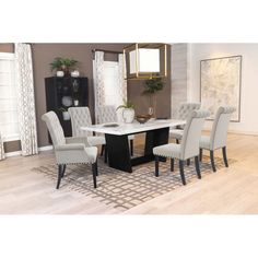 a dining room table with white chairs and a rug on the floor in front of it