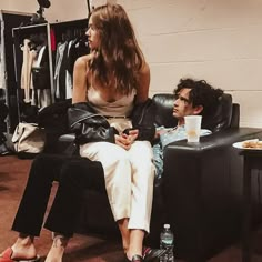 a woman sitting next to a young man on a black leather couch in a room