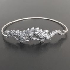 Dragon Bangle Bracelet. A silver tone dragon charm will be transformed into a dragon bangle bracelet with bangle band choice of silver filled or sterling silver. This Chinese New Year bracelet also comes in gold tone with a brass or 14k gold filled bangle band. Personalize your dragon bracelet with custom initial charms or birthstone charms to create a customized dragon charm bracelet;http://www.etsy.com/shop/FrostedWillow?section_id=6596366Please specify size in notes to seller during checkout Adjustable Sterling Silver Dragon Jewelry, Adjustable Sterling Silver Jewelry With Dragon Design, Mystical Dragon, Chinese New Year Gift, Chinese New Year Gifts, Dragon Bracelet, Dragonfly Jewelry, Chinese Jewelry, Dragon Lover