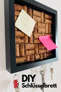 a cork bulletin board with keys hanging on it and a note pinned to the cork