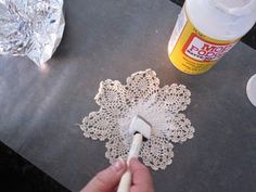 someone is painting the doily with white paint