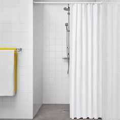 a white shower curtain in a bathroom next to a bathtub with yellow towels on it