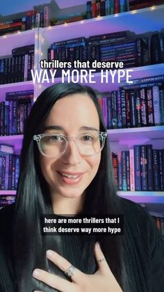 a woman wearing glasses and holding a cell phone in front of a bookshelf