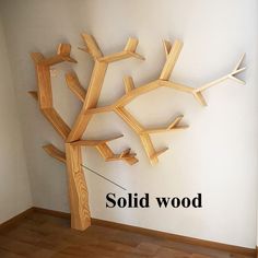 a wooden tree sculpture sitting on top of a hard wood floor next to a white wall