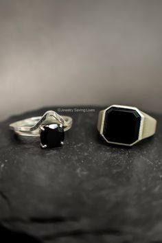 two rings sitting on top of a rock with a black stone in the middle,