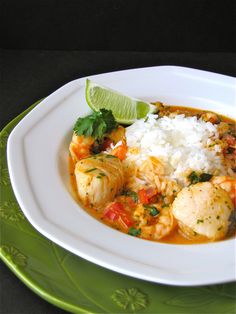 a white plate topped with shrimp and rice next to a slice of lime wedges