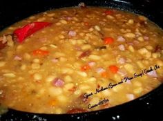 a pot filled with beans and carrots cooking on top of a stove burner