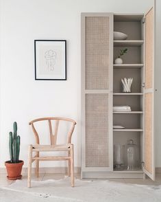 a white room with a chair, table and bookcase on the floor in front of it