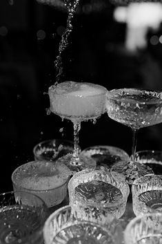 there are many wine glasses on the table with water pouring from one glass to another