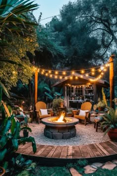 a fire pit surrounded by chairs and lights in the middle of a garden with lots of greenery