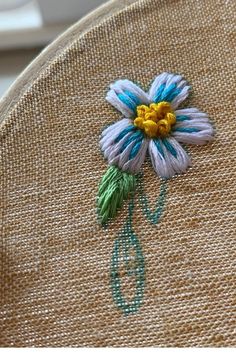 a close up of a flower embroidered on a piece of burlied fabric with green thread