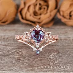 an engagement ring with a pink and blue stone surrounded by white diamonds on a wooden surface