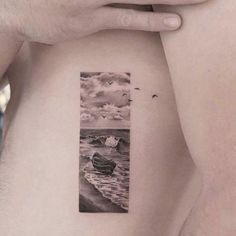 a man with a small boat on the beach behind his back shoulder and arm tattoo