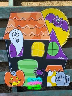 a wooden house with halloween decorations painted on the front and sides, along with pumpkins