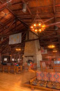 the inside of a restaurant with wooden tables and couches in front of a fire place