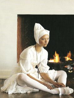 a woman sitting on the floor in front of a fire place