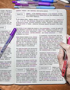 a person is writing in a notebook with pens and markers on the desk next to them