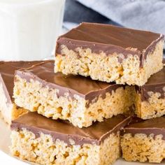 five pieces of chocolate covered rice krispy treats stacked on top of each other with a glass of milk in the background