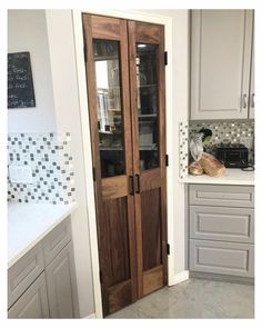 a kitchen with white cabinets and wooden doors